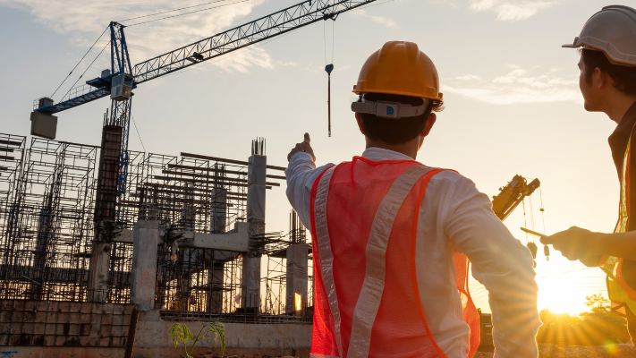 Civil engineering team reviewing infrastructure construction site at sunset